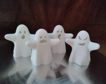 Könnte beinhalten: Vier weiße Geisterfiguren mit verschiedenen Gesichtsausdrücken. Jeder Geist hat ausgestreckte Arme und eine einfache, abgerundete Form. Die Geister sind auf einer reflektierenden Oberfläche angeordnet, für Halloween-Dekorationen.