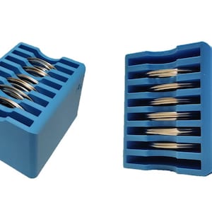 May include: A blue plastic storage case with multiple slots for holding round objects, such as coins or jewelry. The case is filled with round objects.