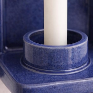 Peut inclure: Gros plan sur un bougeoir en c&eacute;ramique bleu avec une bougie blanche. Le bougeoir a une surface textur&eacute;e et une ouverture circulaire pour maintenir la bougie. Le design est simple et moderne.