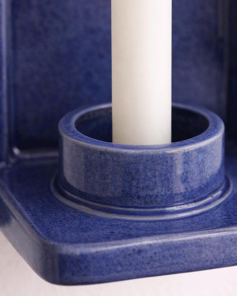 Peut inclure: Gros plan sur un bougeoir en c&eacute;ramique bleu avec une bougie blanche. Le bougeoir a une surface textur&eacute;e et une ouverture circulaire pour maintenir la bougie. Le design est simple et moderne.