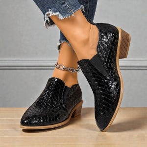 Pu&ograve; includere: Stivaletti neri in pelle intrecciata con tacco basso. Le scarpe hanno la punta a punta e pannelli laterali elastici per una facile calzata. Gli stivaletti sono mostrati con jeans strappati.