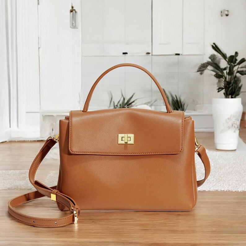 May include: A brown leather handbag with a gold clasp and a detachable shoulder strap.
