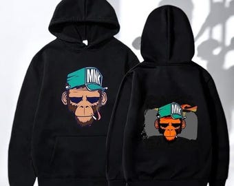 May include: A black hooded sweatshirt featuring a graphic print of a monkey wearing a teal cap with the text MNK on the front and back. The monkey illustration includes dark sunglasses and a cigarette, displayed on the chest and back.