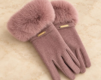May include: A pair of mauve gloves featuring a thick, plush faux fur cuff at the wrist. Each glove is accented with a small, rectangular gold-toned metal bar detail positioned horizontally just below the fur trim on the back of the hand.