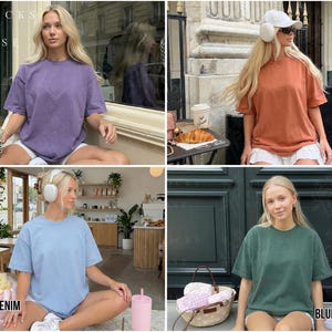 May include: Four oversized t-shirts in different colors: grape, rust, washed denim, and blue spruce. Each shirt has a crew neck and short sleeves. The shirts are displayed on a person sitting down. The text "MOCKS BY ROSE" is at the top left.