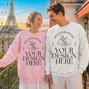 Könnte beinhalten: Ein Mann und eine Frau tragen passende Sweatshirts. Das Sweatshirt der Frau ist hellrosa, das des Mannes ist weiß. Beide Sweatshirts tragen den Text "MOCKSBYROSE" und "YOUR DESIGN HERE" sowie eine Zitronengrafik.
