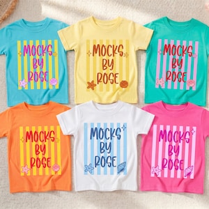 May include: Six colorful t-shirts with the text "MOCKS BY ROSE" in a vertical striped design. The shirts are in shades of blue, yellow, green, orange, white, and pink. Each shirt has a seashell and starfish graphic.