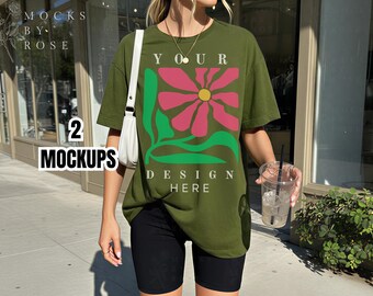 Può includere: T-shirt verde oliva con un grande disegno floreale rosa, verde e giallo. Il testo "YOUR DESIGN HERE" è stampato sulla maglietta. La modella indossa pantaloncini neri e tiene in mano un bicchiere di plastica trasparente con ghiaccio e una cannuccia.