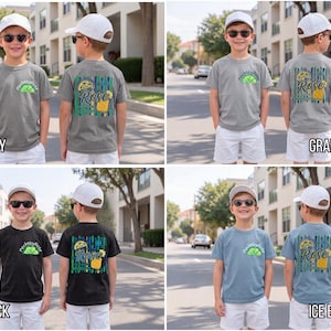 May include: A collection of children's t-shirts in various colors, including grey, black, and blue. Each shirt features a graphic design on the front and back, with the word "Rose" and a lime design. The shirts are displayed on young children.