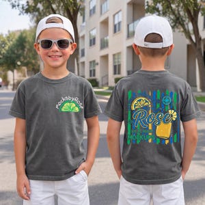 May include: Two views of a charcoal gray t-shirt with a white baseball cap. The front of the shirt has a lime graphic and the text "mocksbyRose". The back of the shirt has a cocktail graphic with the text "Rose Summer Mockup".