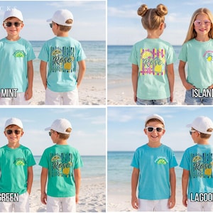 May include: Four children's t-shirts in various colors: Chalky Mint, Island Reef, Island Green, and Lagoon Blue. Each shirt features a front and back design with the word "Rose" and a tropical-themed graphic. The shirts are displayed on a beach setting.