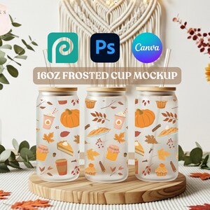 May include: Three 16oz frosted glass cups with bamboo lids and straws, decorated with fall-themed illustrations of pumpkins, leaves, and baked goods. The cups are displayed on a wooden stand, with the text "16OZ FROSTED CUP MOCKUP" above them.