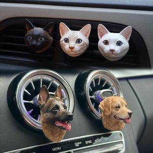 May include: Car air vent clips featuring animal head designs. Three white cat head clips and two dog head clips, one brown and one golden.