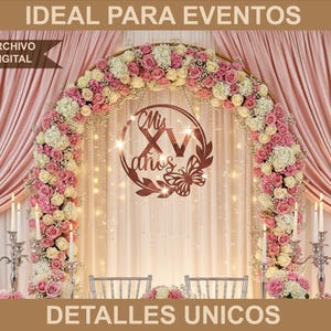 May include: A decorative archway adorned with pink and white flowers, featuring a central sign that reads "Mis XV años" with a butterfly accent. The backdrop includes pink drapes and string lights, creating an elegant setting for a celebration.