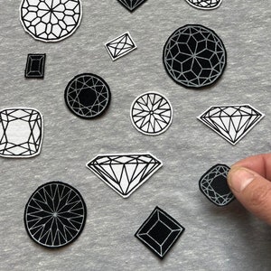 May include: A grey sweatshirt with black and white diamond-shaped patches. The patches are of various sizes and shapes, and some have a geometric pattern.