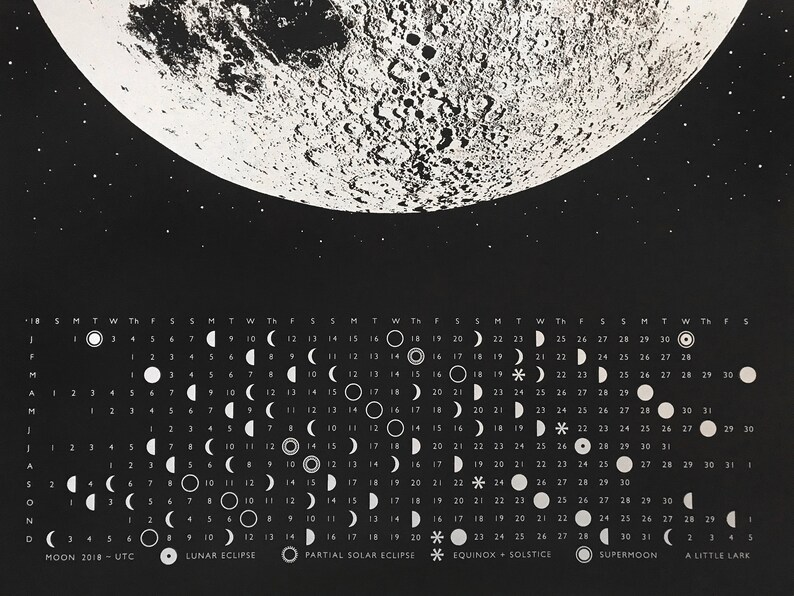May include: A black and white calendar featuring a full moon with a detailed surface texture. The calendar shows the phases of the moon for each day of the year 2018. The calendar also includes dates for lunar eclipses, partial solar eclipses, equinoxes, solstices, and supermoons.
