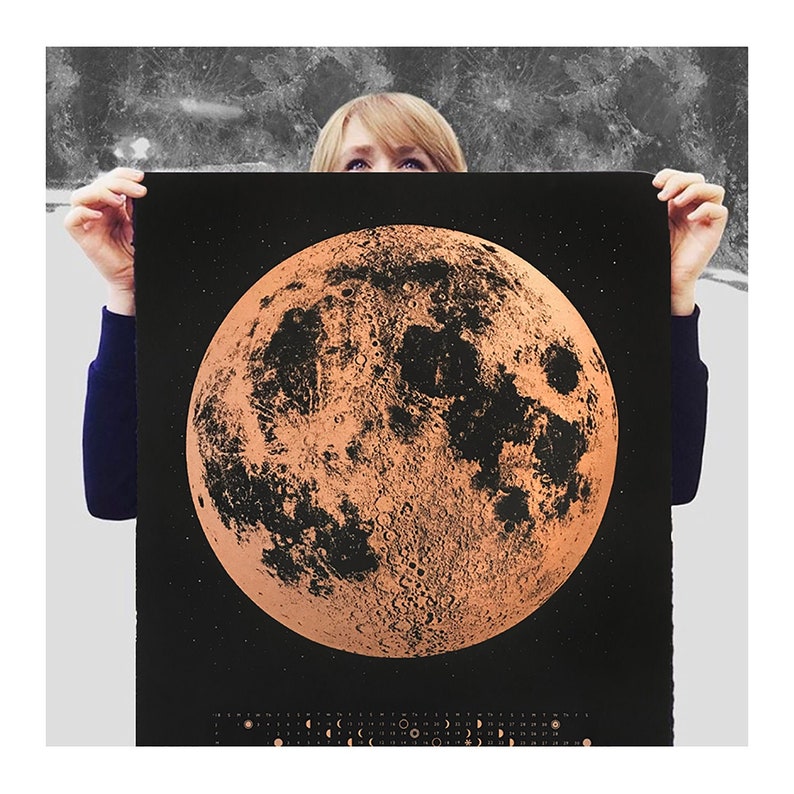 May include: A black and copper poster featuring a detailed illustration of the moon with a calendar of moon phases at the bottom.