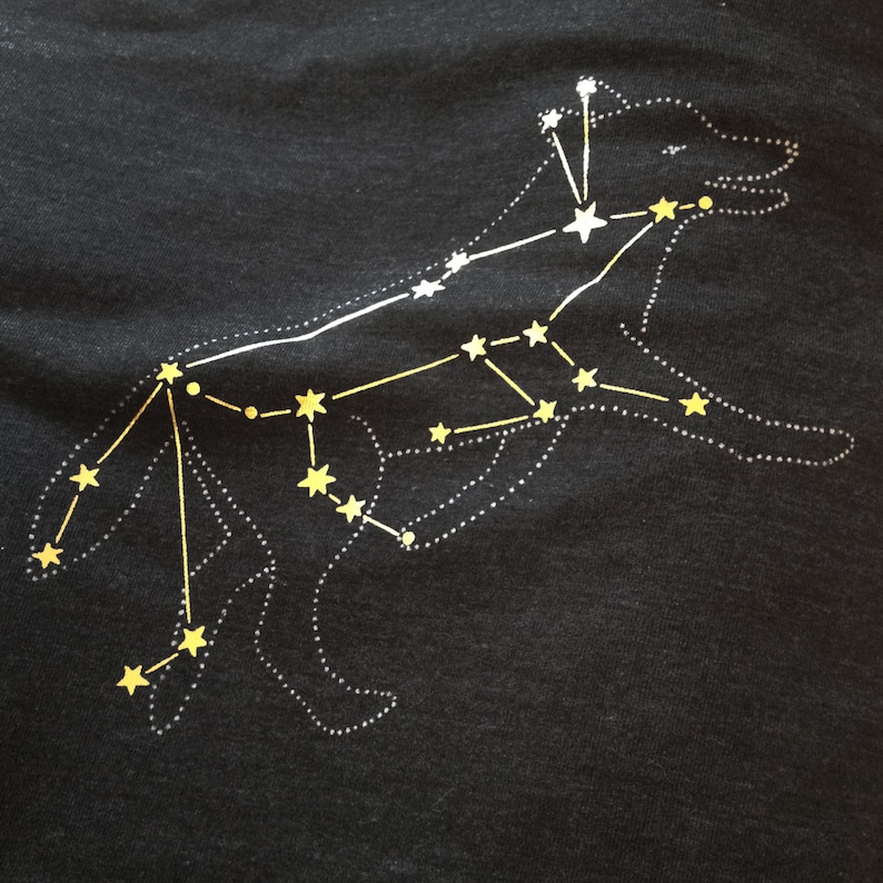May include: A black t-shirt with a white outline of a dog constellation with yellow stars.