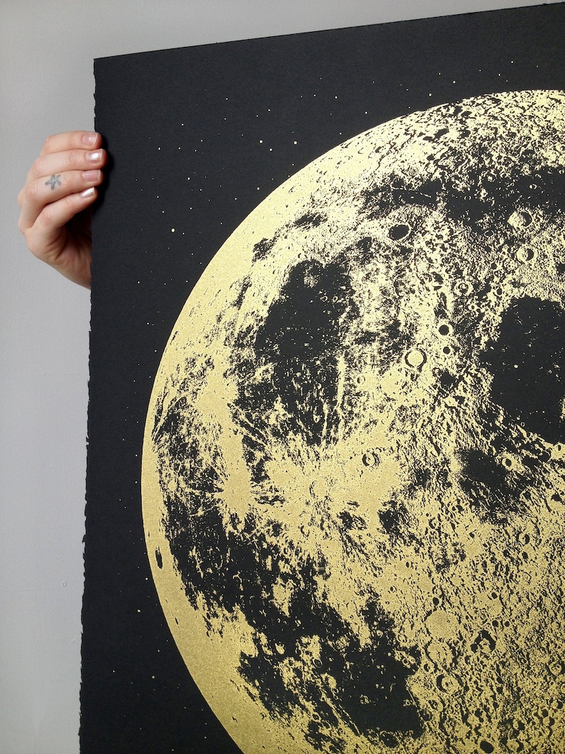 May include: A black and gold print of the moon with a detailed depiction of its surface. The moon is surrounded by a black background with small white stars.
