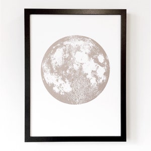 May include: A framed print of a beige moon with a white surface, showing the moon's craters and texture.