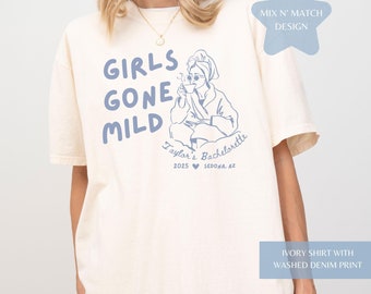 May include: Ivory t-shirt with a blue graphic print of a woman in a robe holding a mug. The text "Girls Gone Mild" is printed in a blue, stylized font. The text "Taylor's Bachelorette 2025 SEDONA, AZ" is printed below the graphic.