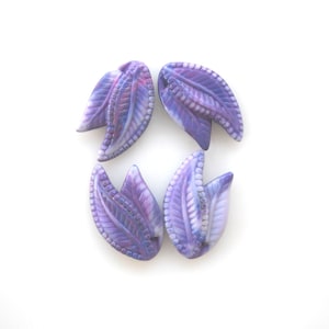 May include: Four purple glass beads shaped like leaves with a white swirl pattern.