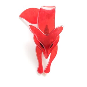 Puede incluir: Un broche de zorro de pl&aacute;stico rojo. El zorro est&aacute; mirando hacia adelante con la cabeza inclinada hacia abajo. El broche es un dise&ntilde;o simple sin adornos.