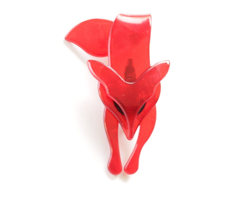 Puede incluir: Un broche de zorro de pl&aacute;stico rojo. El zorro est&aacute; mirando hacia adelante con la cabeza inclinada hacia abajo. El broche es un dise&ntilde;o simple sin adornos.
