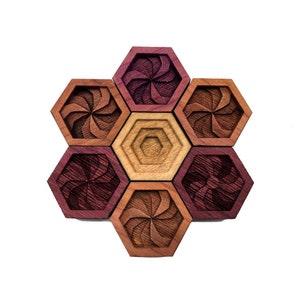 May include: A set of six hexagonal wooden coasters with a swirling pattern in shades of brown and purple. The coasters are arranged in a honeycomb pattern.