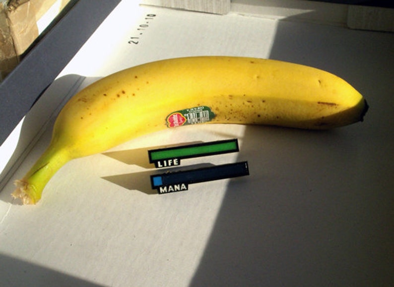 May include: A yellow banana with a green sticker on it.  Two progress bars are below the banana, one green labeled "LIFE" and one blue labeled "MANA".