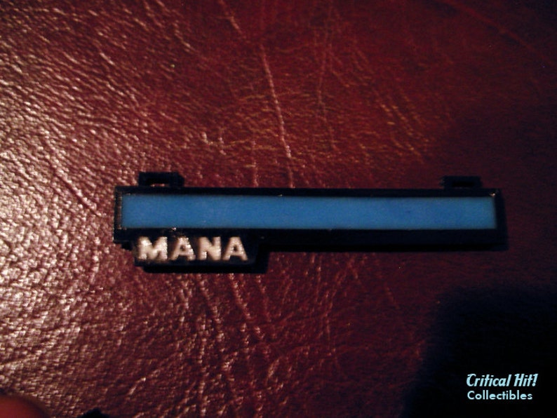 May include: A black plastic mana bar with a blue bar inside and the word "MANA" printed in white.