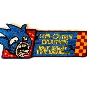 May include: A rectangular embroidered patch featuring a blue cartoon character head with a distressed expression on a red background. The blue rectangular section contains the yellow embroidered text: I CAN OUTRUN EVERYTHING BUT WHAT I'VE DONE.