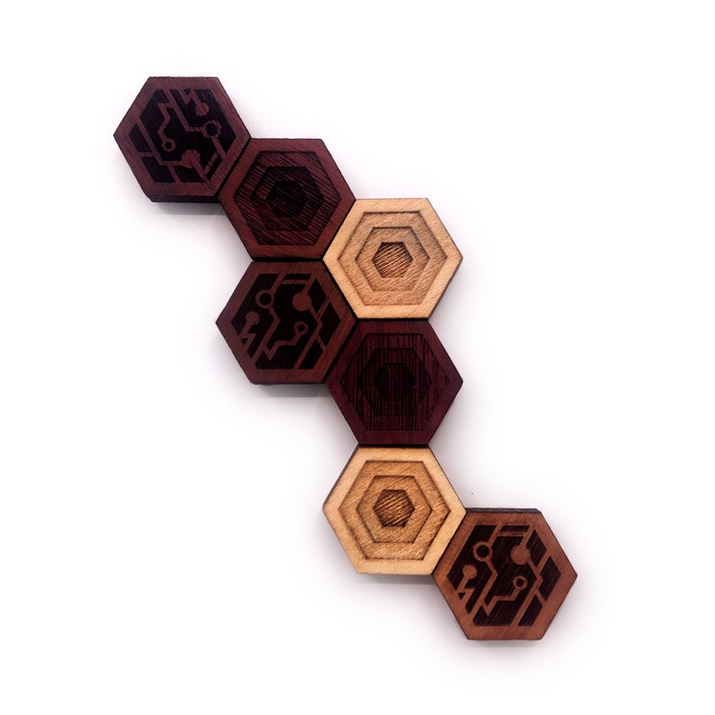 May include: A set of hexagonal wooden tiles with a circuit board design. The tiles are arranged in a staggered pattern, with the top tile being brown, the next tile being light brown, and so on. The tiles are made of different shades of brown wood.