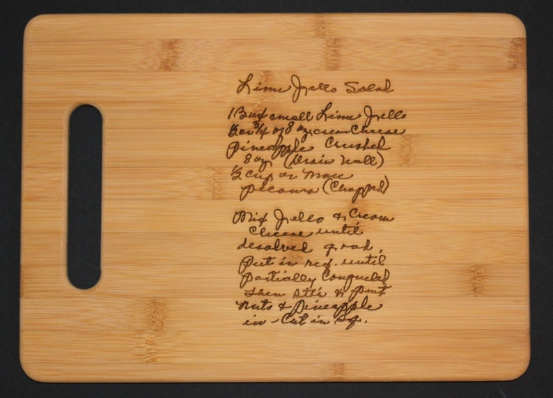 May include: A close-up of a wooden cutting board with a handwritten recipe for Lime Jello Salad. The recipe includes ingredients like lime jello, cream cheese, pineapple, and whipped cream.