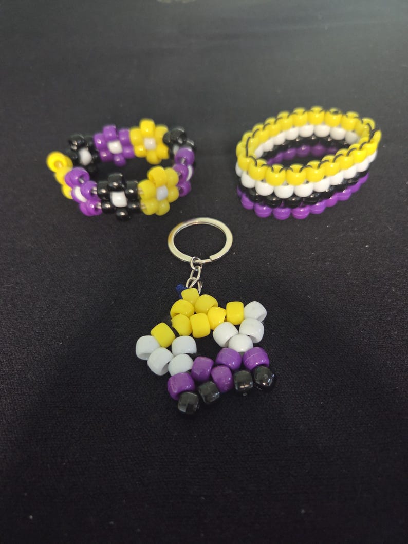 Peut inclure: Trois accessoires perl&eacute;s : un porte-cl&eacute;s et deux bracelets. Le porte-cl&eacute;s est en forme d'&eacute;toile et les bracelets sont ronds. Les perles sont jaunes, blanches, violettes et noires. Les bracelets ont un motif floral.