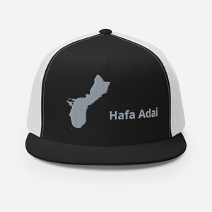 Könnte beinhalten: Schwarze und weiße Trucker-Kappe mit einem grauen Umriss der Insel Guam und dem Text "Hafa Adai" in Grau.