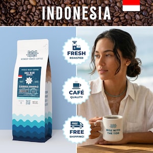 May include: A bag of Bali Blue whole bean coffee from Indonesia, with the text "Wonder Waves Coffee." The bag has a blue wave design. A woman holds a mug that says "Rise with the Tide."