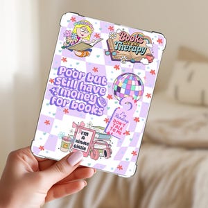 May include: A clear tablet case with a colorful design featuring the text "Poor but still have money for books." Other text includes "Books are my therapy" and "I'm a Kindle Girlie." The case has a checkerboard pattern with flowers and a disco ball.