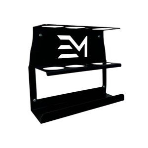 May include: Black metal wall-mounted organizer with three circular openings on top, three on the middle shelf, and a curved bottom shelf. The design includes a white logo with the letters "EM".