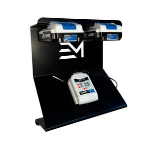 May include: Black metal battery charging station with two white and blue HART batteries and a white charger. The station has a white logo and a sloped design. The charger displays red and green lights.