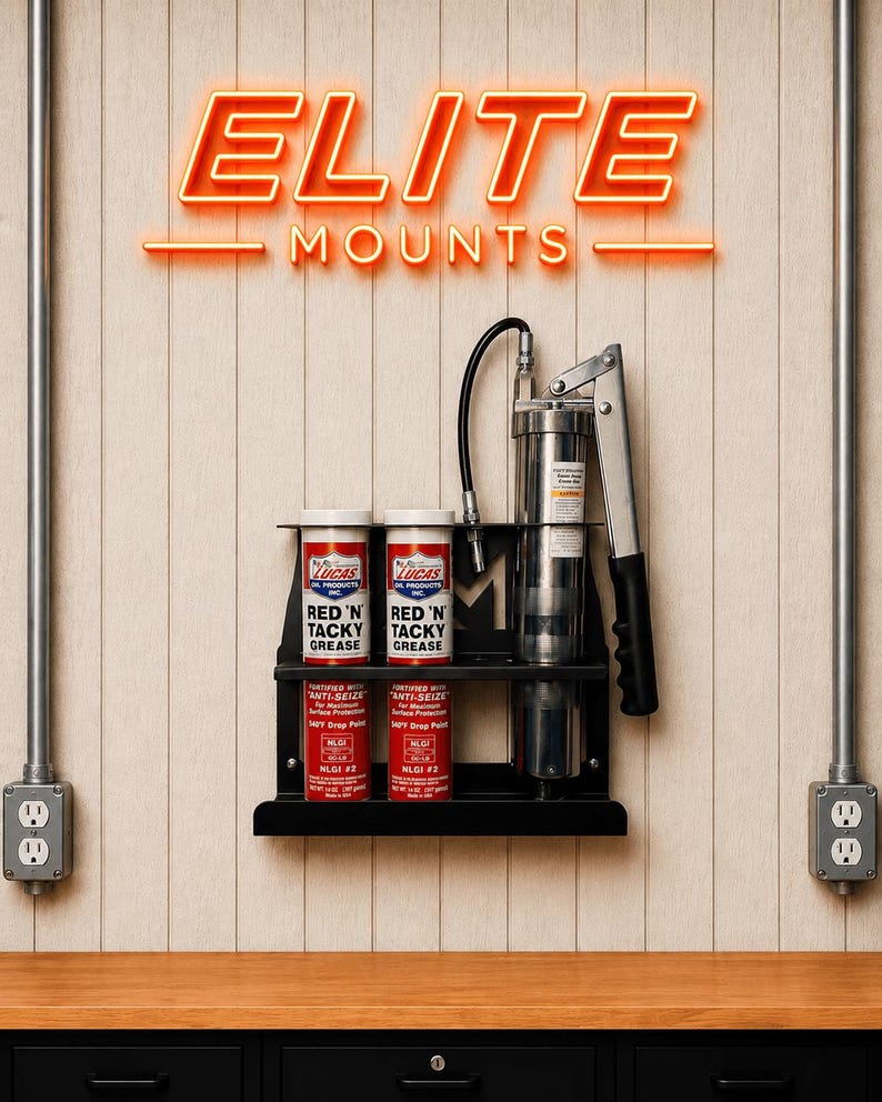 May include: A black metal wall-mounted shelf holding two red and white Lucas Red 'N' Tacky Grease cans, two smaller cans, and a grease gun. The neon sign above reads "ELITE MOUNTS". The background is a light wood-paneled wall.