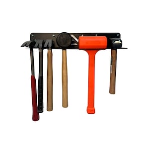 May include: A black metal tool holder with six hammers. The hammers have wooden and black handles, and one is bright orange. The holder is mounted on a white background.