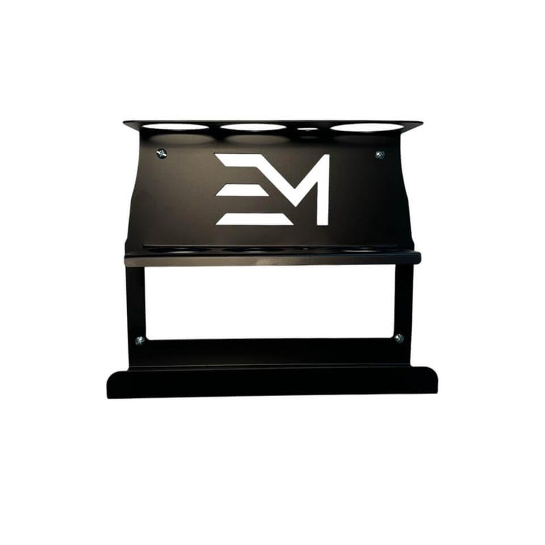 May include: Black metal rack with a white logo. The rack has multiple slots at the top and a shelf below. The logo is a stylized "EM" design. The rack is designed to hold items.