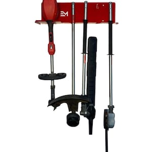May include: A red metal wall-mounted rack holding various yard tools. The rack has the letters "EM" on it. Tools include a red string trimmer, and several other tools with black and silver components. The tools are hanging vertically.