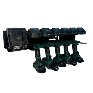 May include: A black metal drill and battery organizer with six green and black drills and six batteries. A charger is on the left side. The organizer is designed to hold power tools and their accessories.