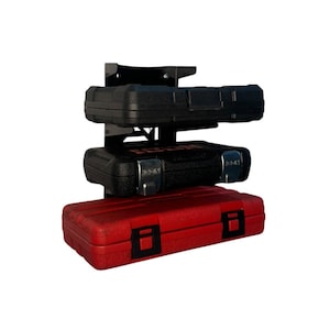 May include: A three-tiered tool storage system with a black metal frame. The system holds three toolboxes: a black one on top, a black one in the middle, and a red one at the bottom. Each toolbox has a secure latch.