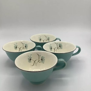 May include: Four teal teacups with white interiors and a delicate floral design. The cups have a silver rim and a small handle.