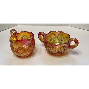 May include: A set of two amber glass bowls with a scalloped edge and intricate etched designs. The bowls have two handles each and are perfect for serving sugar or cream.