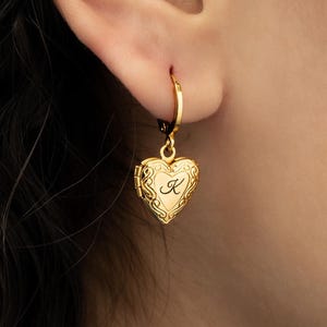 May include: Gold heart-shaped locket earring with a hoop and a letter 'K' engraved on the front.