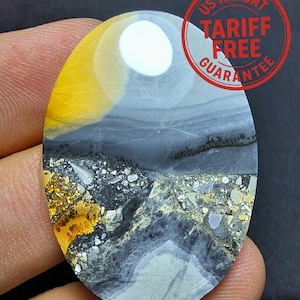 May include: An oval gemstone with a distinctive pattern. The stone displays a mix of colours, including yellow, grey, black, and white. The top section has a yellow and white gradient, leading to grey and black layers. The bottom part has a mosaic-like appearance. The text "US Import Tariff Free Guarantee" is stamped on the top right.